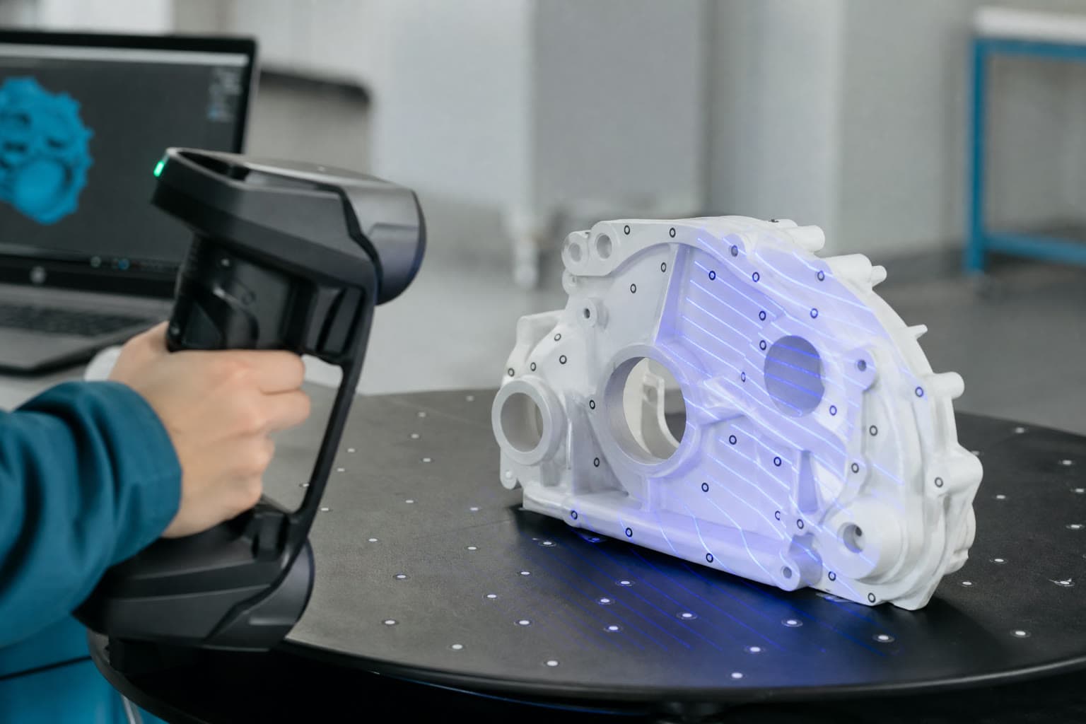 Handscanner erfasst ein mattiertes Gussgehäuse mit blauen Laserlinien